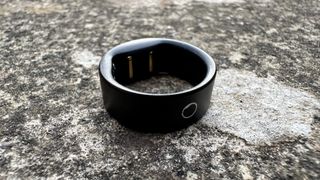 Circular Ring Slim black smart ring in concrete.